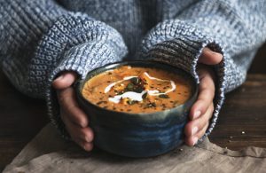 Female hands holding a bowl of pumpkin soup